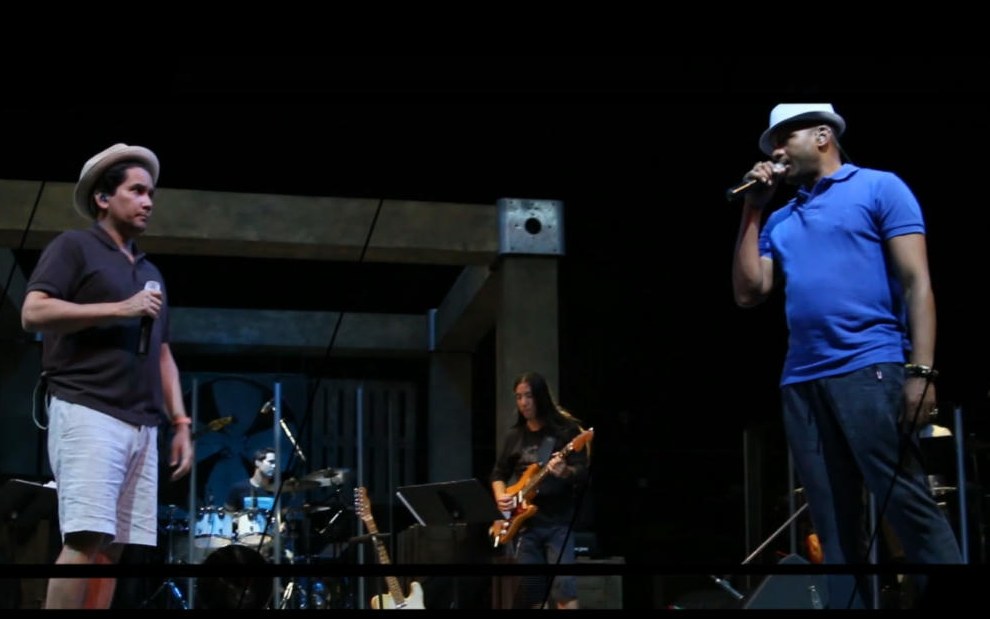 Dos cantantes ensayando en el escenario con la banda